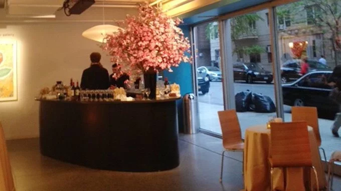 Lobby of New York Live Arts, large. bar with pink flowers and windows looking out to New York City street